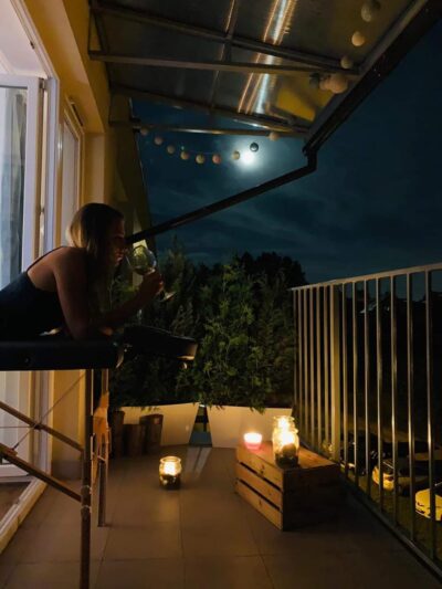 Dziewczyna na stole do masażu, na balkonie, w tle ciemne niebo